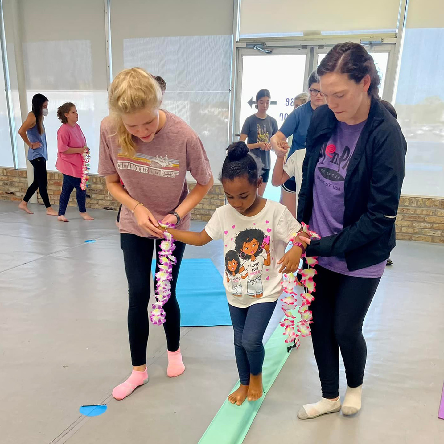 Little girl walking on floor beam with helpers